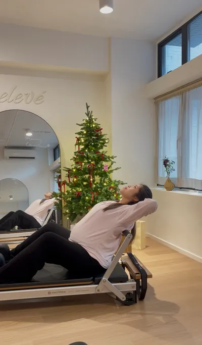Pregnant client reclining on a reformer at Relevé Studio Sheung Wan during a prenatal Pilates session