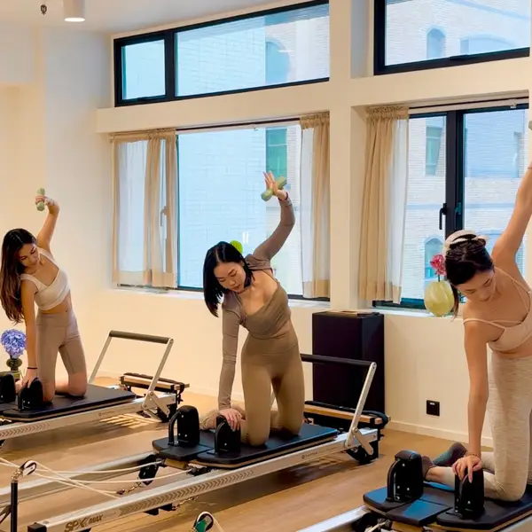 Group reformer Pilates class with three clients training in natural light at Relevé Studio Sheung Wan